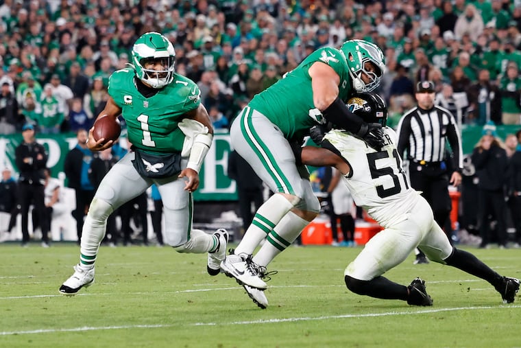 Eagles quarterback Jalen Hurts runs with the ball as Lane Johnson blocks Jaguars linebacker Ventrell Miller on Sunday.