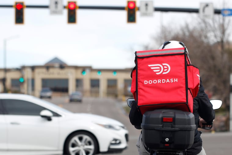 A DoorDash food delivery motorcycle rider waits for the traffic light to change March 30, 2020, in Lone Tree, Colo.