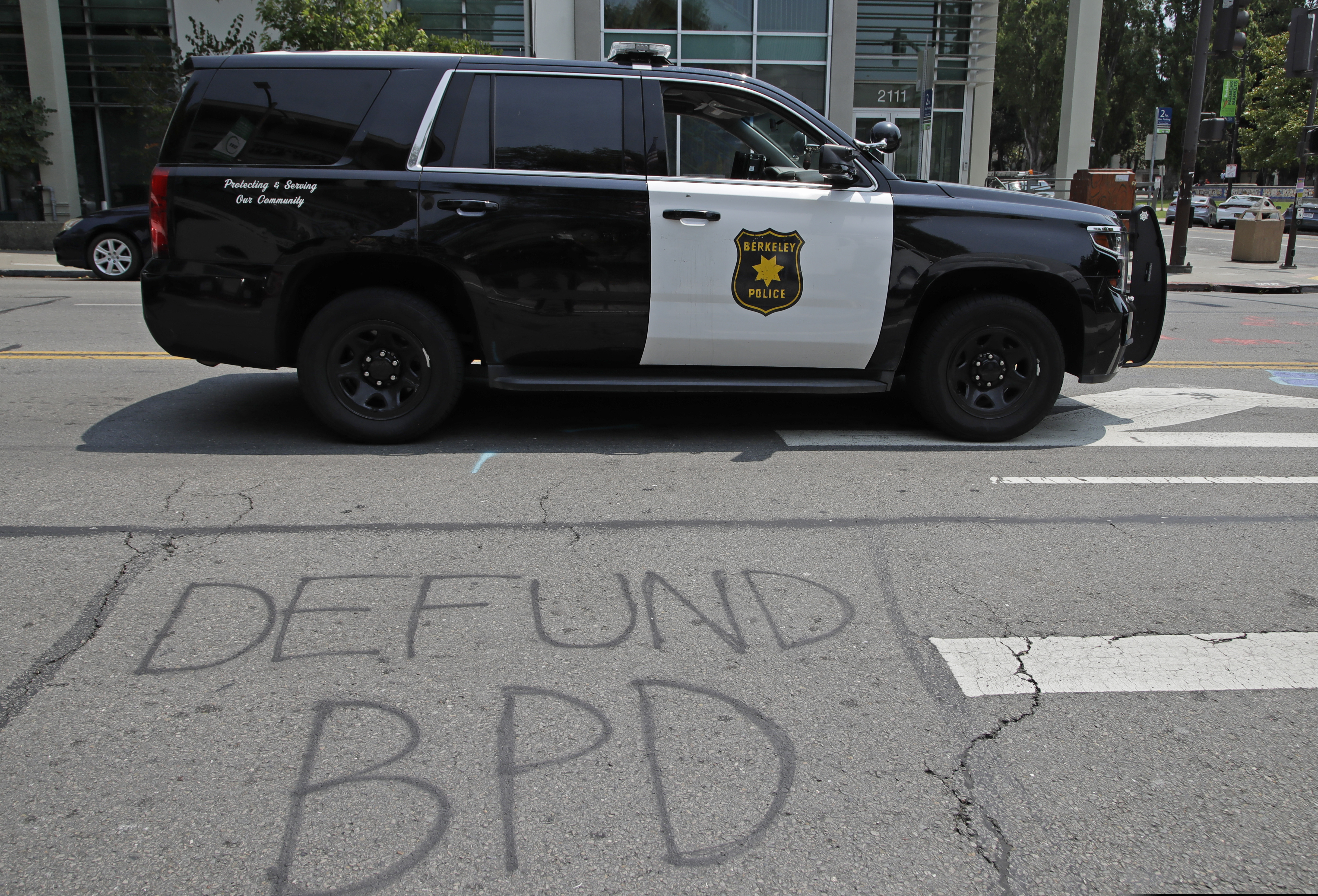 A Berkeley police vehicle waits at a stop light near graffiti calling for the defunding of the Berkeley police department on Wednesday in Berkeley, Calif. The city of Berkeley moved forward Wednesday with a proposal to eliminate police from conducting traffic stops and instead use unarmed civilian city workers as part of a broad overhaul of law enforcement. The City Council also set a goal of cutting the police budget by 50%.