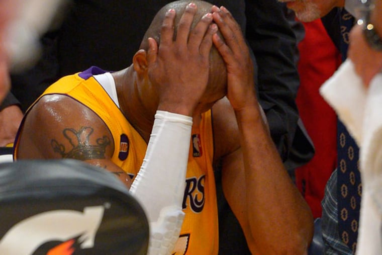 Kobe Bryant puts his head in his hands as trainer Gary Vitti looks on after being injured during the second half of their NBA basketball game against the Golden State Warriors, Friday, April 12, 2013, in Los Angeles. The Lakers won 118-116. (Mark J. Terrill/AP)