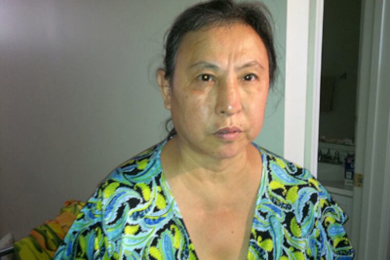 Minh Tran, 51, speaks Tuesday after she was beaten and robbed by three boys Monday in her tiny Juniata Park apartment. (Julie Shaw / Staff)