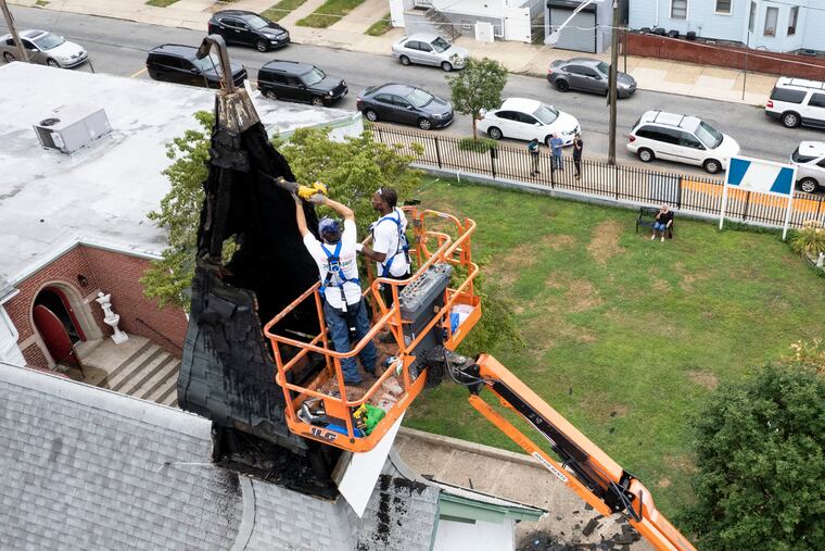 Roofers work on the fire-damaged steeple at Grace Episcopal Church and the Incarnation in Port Richmond on Tuesday.