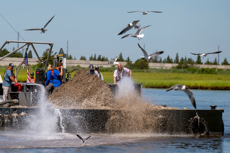 High-pressure water cannons blast oyster shells off a barge into the waters of the Mullica River, where they help bolster the oyster population on reefs below.