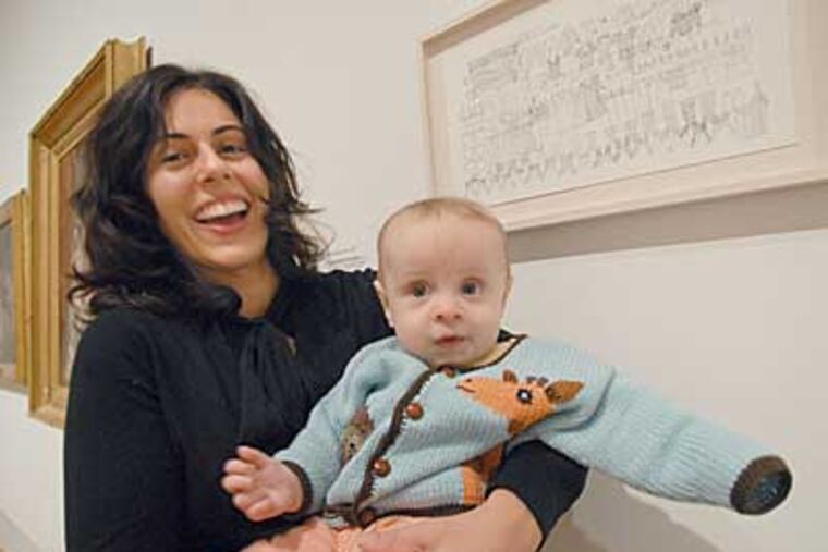 Artist Mia Rosenthal with son Kirby at the Pennsylvania Academy of the Fine Arts, next to her "Postpartum Portrait," an inventory of her closet. (APRIL SAUL / Staff Photographer)