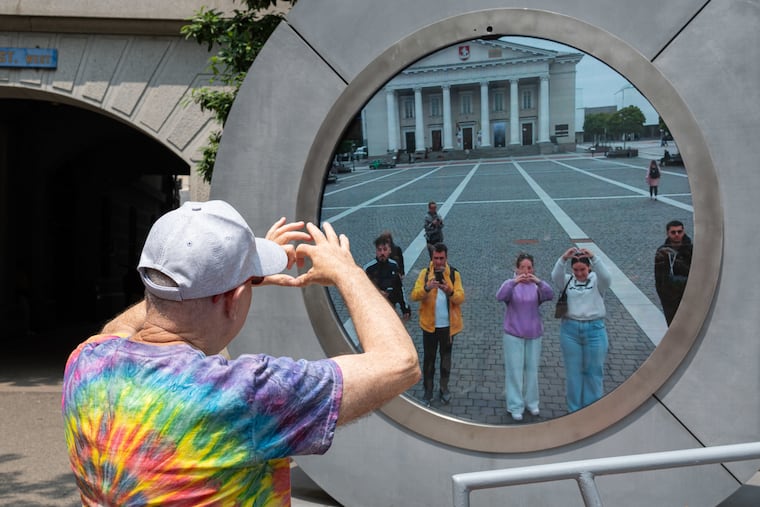 Steve Farkas holds up a heart sign to people in Lithuania at the Philadelphia Portal art installation in City Hall on Wednesday, June 11, 2025.
