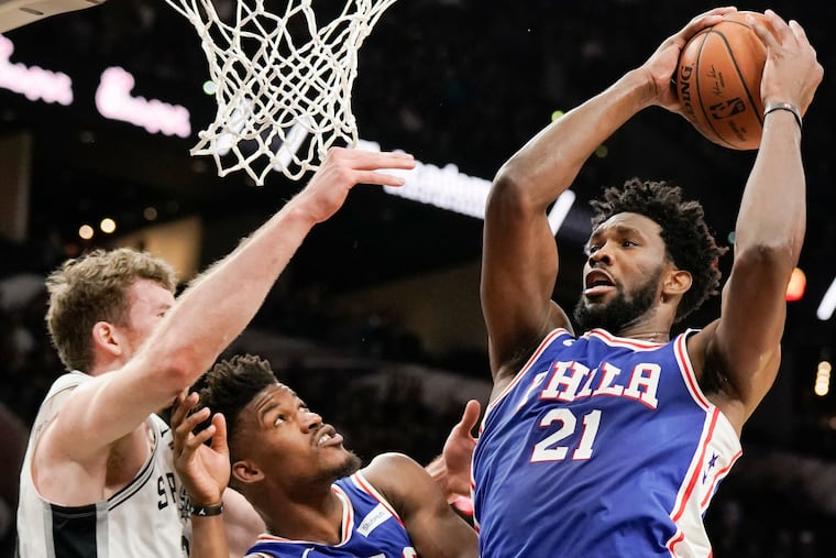 Joel Embiid tries to shoot past the Spurs' Jakob Poeltl (left) and teammate Jimmy Butler during the first half of the Sixers' loss.