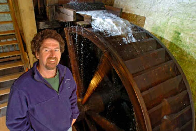Rick Fellows next to the waterwheel of the Newlin Grist Mill in Glen Mills. His continuous efforts since 1990 have kept the works running smoothly.