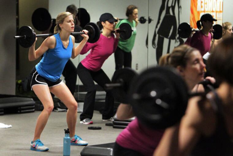 Julie Long, left, does a squat track in AGX (formerly Adrenaline Group Xercise) owner Jacob McLendon's BodyPump/CXWORK combo class in Chamblee, Georgia, December 22, 2012. (Phil Skinner/Atlanta Journal-Constitution/MCT)
