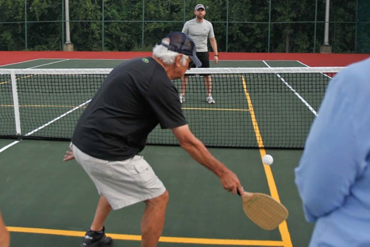 Dan Marlowe, center, demonstrates a strategic shot with instructor Jay Hubert, center back, as others look on during a pickleball class at Kennedy Recreation Complex in St. Louis on July 15, 2014. The class, offered by St. Louis Community College, has grown in popularity. (Sarah Conard/St. Louis Post-Dispatch/MCT)