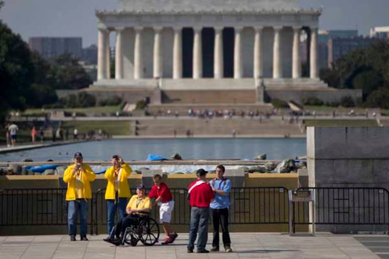 Robert Olson, a Korean War veteran from Iowa, third from left, is pushed in his wheelchair by Zach Twedt, also from Iowa, fourth from left around the National World War II Memorial, Tuesday, Oct. 1, 2013 in Washington. Veterans who had traveled from across the country were allowed to visit the National World War II Memorial after it had been officially closed because of the partial government shutdown. After their visit, the National World War II Memorial was closed again. The Lincoln Memorial is seen in the distance. Congress plunged the nation into a partial government shutdown Tuesday as a long-running dispute over President Barack Obama's health care law stalled a temporary funding bill, forcing about 800,000 federal workers off the job and suspending most non-essential federal programs and services. (AP Photo/Carolyn Kaster)
