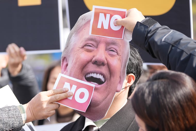 Protesters attach stickers on an image of U.S. President Donald Trump to protest against Trump's demands to multiple countries to send warships to keep the Strait of Hormuz open, near the U.S. Embassy in Seoul, South Korea, March 16.