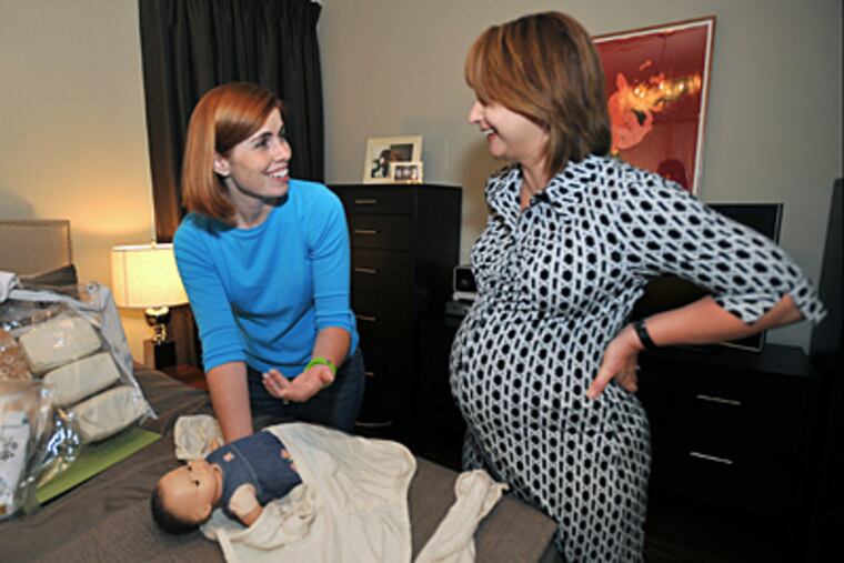 Baby planner Shannon Choe makes a house call to expectant mother Michele Andelbradt in her Villanova home. Choe demonstrates the proper way to swaddle a baby. (Sharon Gekoski-Kimmel / Staff)