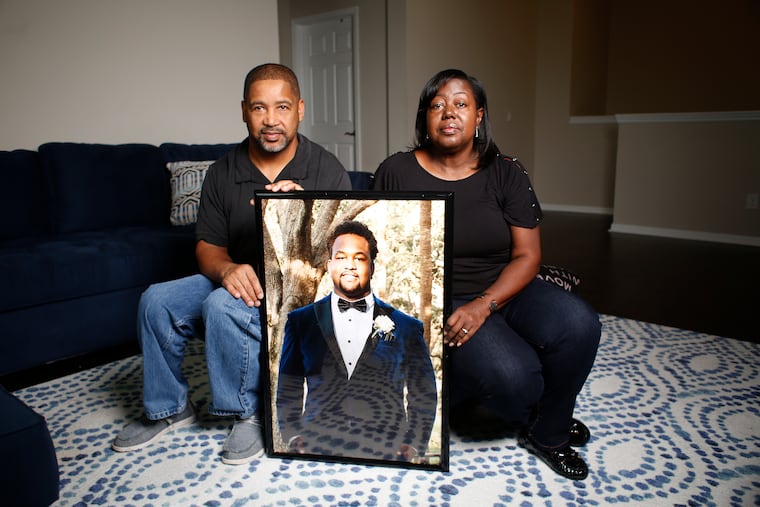 Calvin and Nicole Dickey pose for a portrait in Tampa with a photo of their son, Calvin "CJ" Dickey, who died two days after his first day of football practice at Bucknell University this summer.