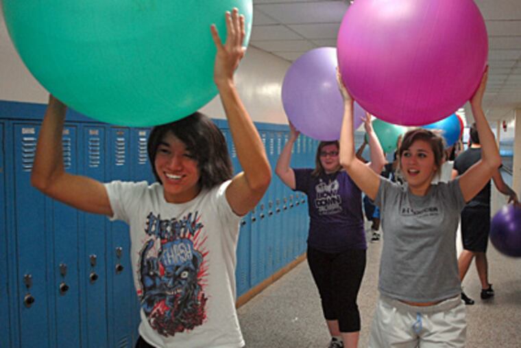 Members of Triton Regional High's HiFive Club run in the hallway with exercise balls. They are (from left) A.J. Aranes, Saraya Bethel, and Kayla Varquez. (Tom Gralish / Staff Photographer)