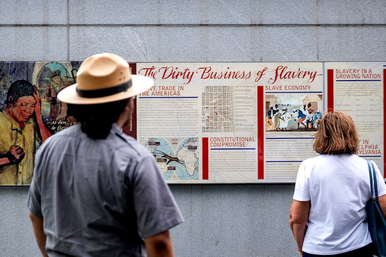 Visitors read signs describing enslavement at the President’s House in Independence National Historical Park Tuesday.