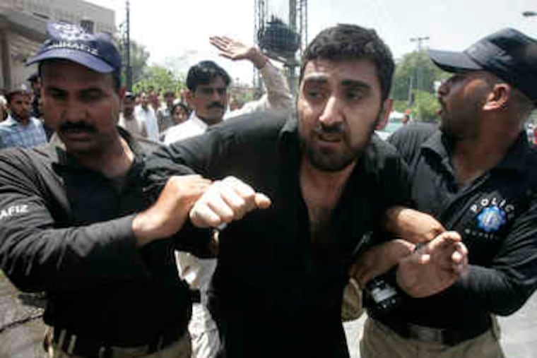 Officers arrest a suspect , one of three detained after a suicide squad using guns and explosives targeted police and the intelligence agency in Lahore, Pakistan. The attack yesterday killed 30 and injured 250, mostly civilians, and was seen as revenge for the army campaign against the Taliban in the Swat Valley. It was the third deadly assault since March in Lahore, far from Taliban strongholds near Afghanistan. A2.