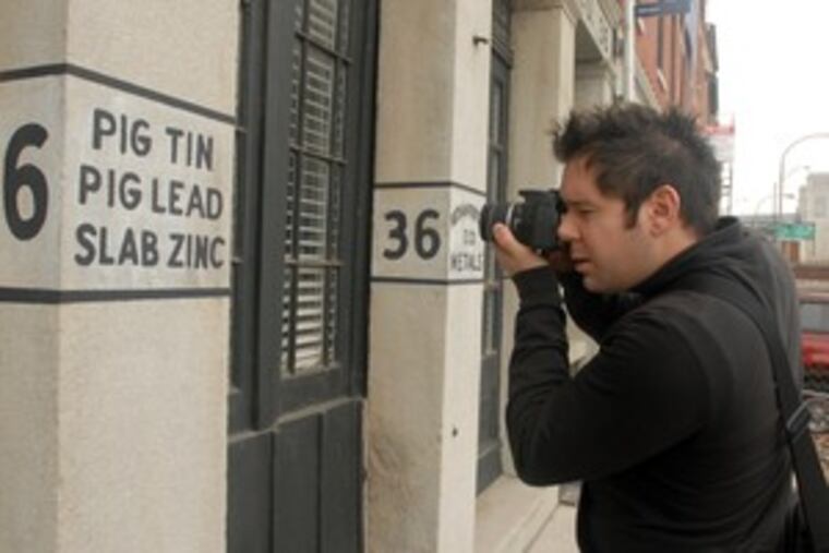 Lawrence O'Toole photographs a touched-up sign on Front Street for the 19th-century Nathan Trotter & Co. He says "ghost sign" technically applies only to an image exposed by a change.