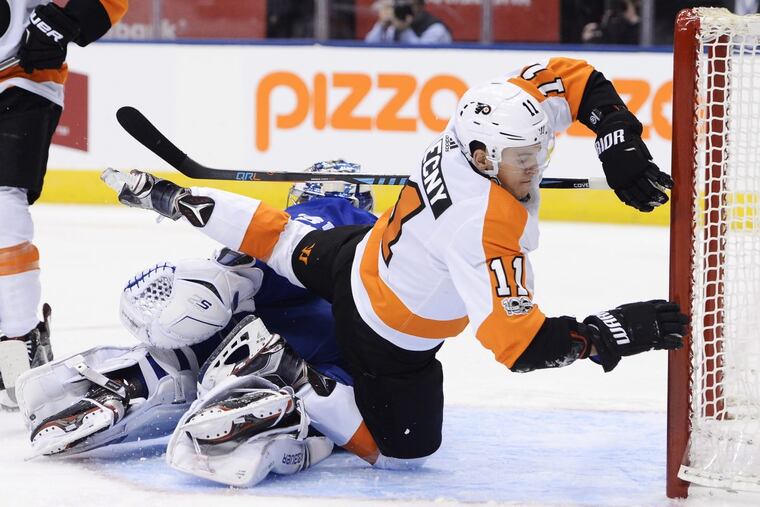 Flyers center Travis Konecny (11) crashes over Maple Leafs goalie Frederik Andersen (31) during a game Saturday.