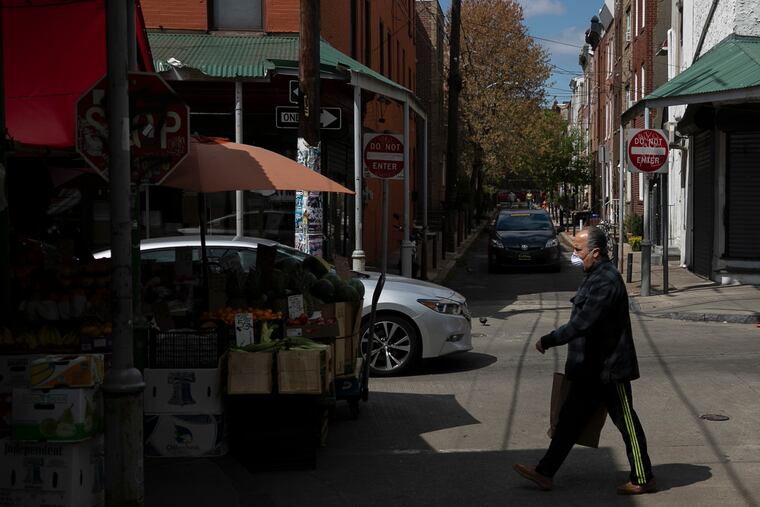 A pedestrian in a mask walks along 9th Street at the Italian Market in Philadelphia on April 11, 2020. All nonessential businesses are closed due to the coronavirus. Restaurants must be takeout or delivery only.