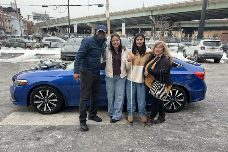 Tianna Graham stands with her mom and sister in front of the car Carvana is gifting her.