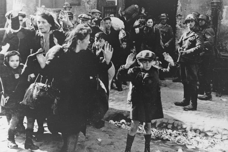 A group of Jews, including a small boy, is escorted from the Warsaw Ghetto by German soldiers in April 1943.
