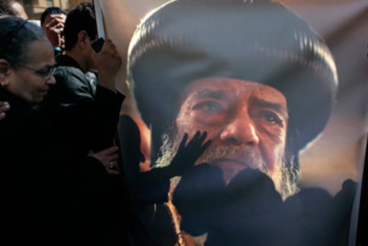 Egyptian Coptic mourners kiss a picture of the ate Pope Shenouda III while gathering outside the Coptic Orthodox Church for the viewing of the body of Pope Shenouda III in Cairo, Egypt, Sunday, March 18, 2012. Pope Shenouda III, the patriarch of the Coptic Orthodox Church who led Egypt's Christian minority for 40 years during a time of increasing tensions with Muslims, died Saturday. He was 88. (AP Photo/Nasser Nasser)