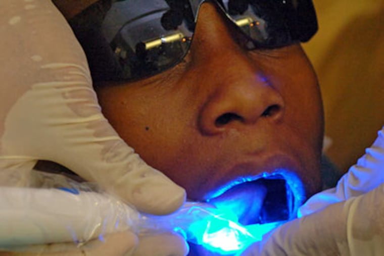 Omar Carter, 12, undergoes treatment to prevent tooth decay on his back teeth. He said he looks forward to his dental visits because they don't hurt and his teeth look clean afterward. (Clem Murray / Staff Photographer)