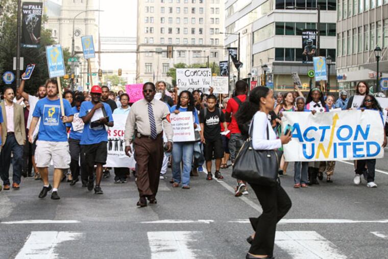 Activists march up JFK Boulevard to the Comcast Center at 17th Street. They rallied outside. (STEVEN M. FALK/Staff Photographer)