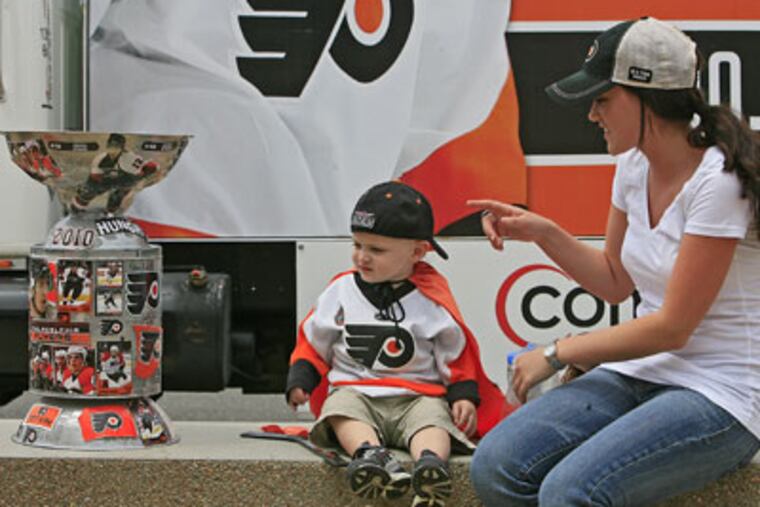 Brenna Philpott (right) from Haddon Twp, NJ, points to a homemade Stanley Cup to her nephew Sam D'Antonio, 17 mo. from Deptford, As fans wait, food experts debate which city has the best cuisine. (Akira Suwa / Staff Photographer )