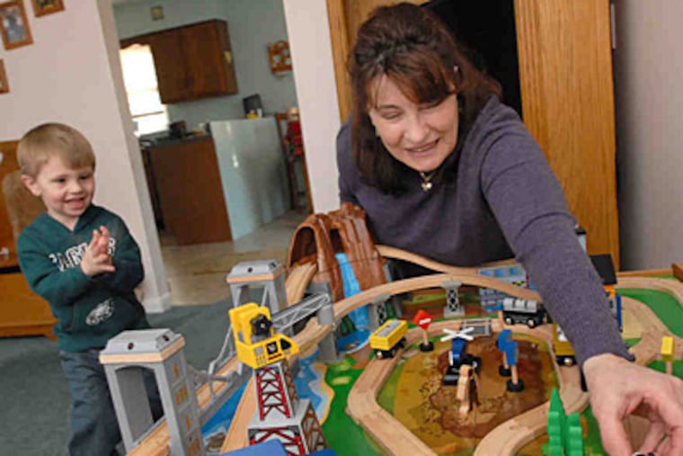 "Without a job," Donna Oxford says, "you can never be relaxed or secure." Here, she plays with grandson Michael in their Coatesville home. (April Saul/Staff)