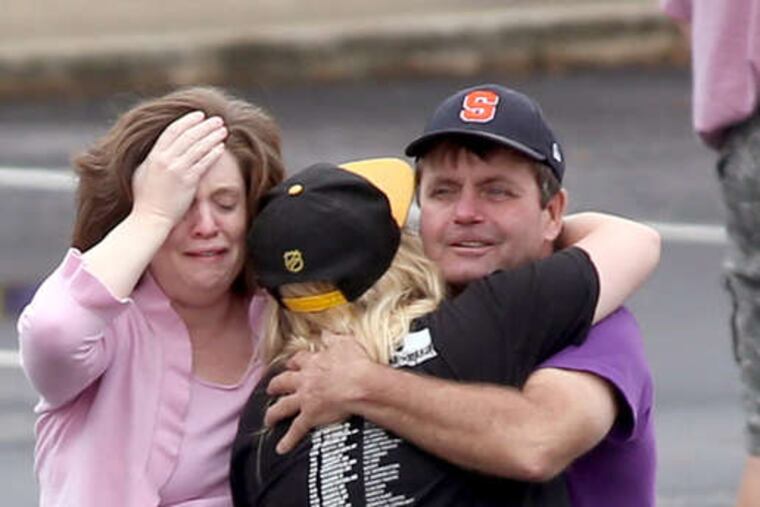 A FedEx worker (right) is consoled as others wait to reunite with relatives. The shooter, a 19-year-old package handler, is believed to have killed himself.