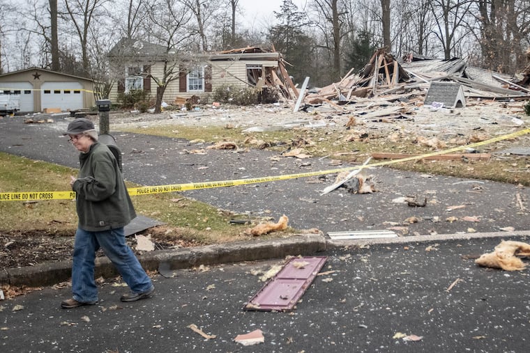 A neighbor walks by the wreckage that use to be a residence in Bucks County. Debris was strewn all over the cul-de-sac where the home was located.