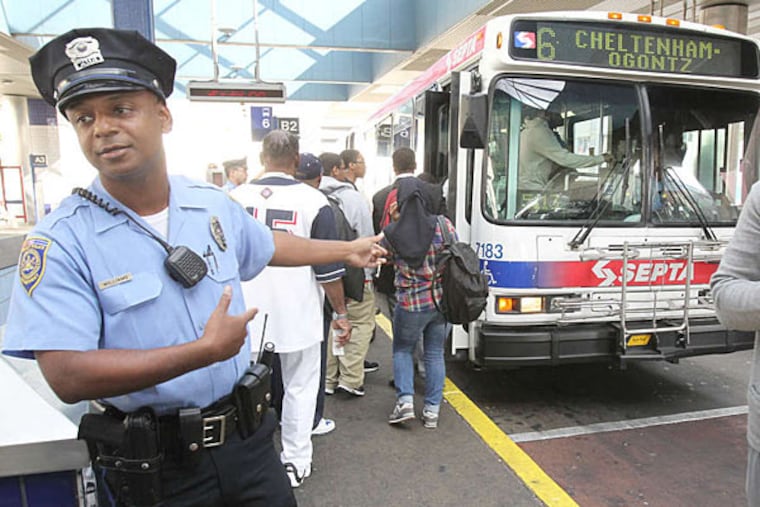 Transit police officer Paul Williams tells students to move along or board the bus at the Olney Transportation Center. (Charles Fox/Staff)