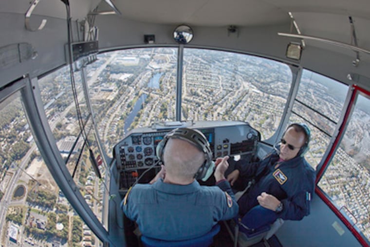 Pilots Mark Kynett (left) and Larry Chambers fly the Navy MZ-3A helium airship near the Lakehurst Naval Air Engineering Station in New Jersey, headed for Toms River and Seaside Heights. (David M Warren / Staff Photographer)