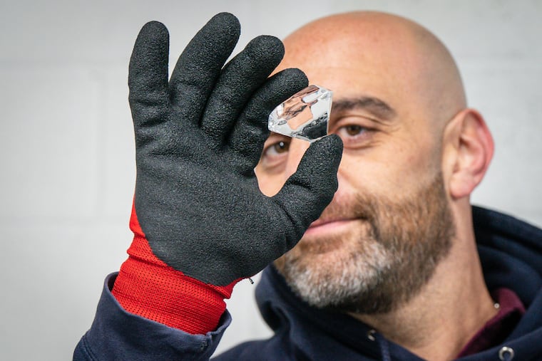 Noah Sokoloff holds up a diamond of clear ice in his warehouse in Ambler.