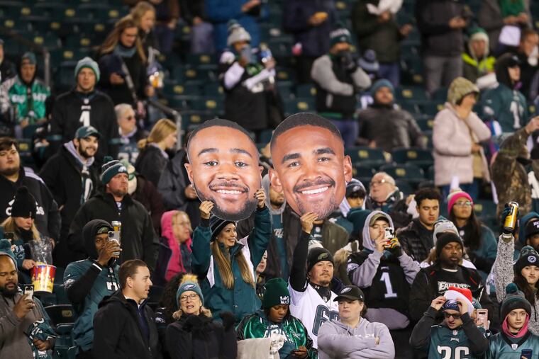 Fans hold up big faces of Philadelphia Eagles running back Miles Sanders (left) and quarterback Jalen Hurts (right).