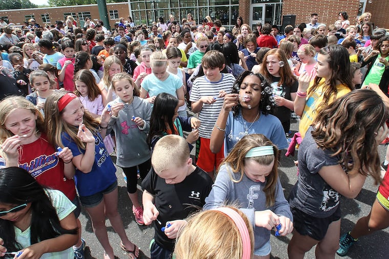 Pupils and staff at Erdenheim Elementary gather on the school’s playground Wednesday to send their wishes — via blown bubbles — out into the cosmos. (STEVEN M. FALK / Staff Photographer)