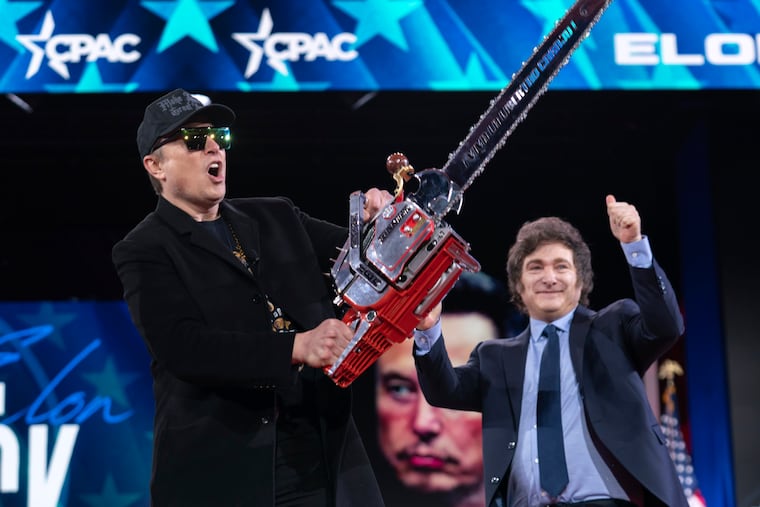 Elon Musk, left, receives a chainsaw from Argentina's President Javier Milei as they arrive at the Conservative Political Action Conference (CPAC) in Oxon Hill, Md., on Thursday, Feb. 20, 2025.