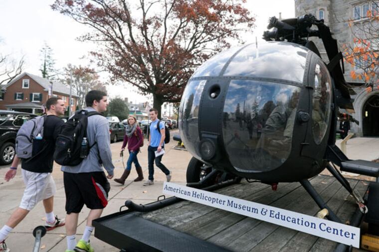 Students walk past an MH-6J helicopter, on loan from the American Helicopter Museum in West Chester. ( ED HILLE /Staff Photographer )