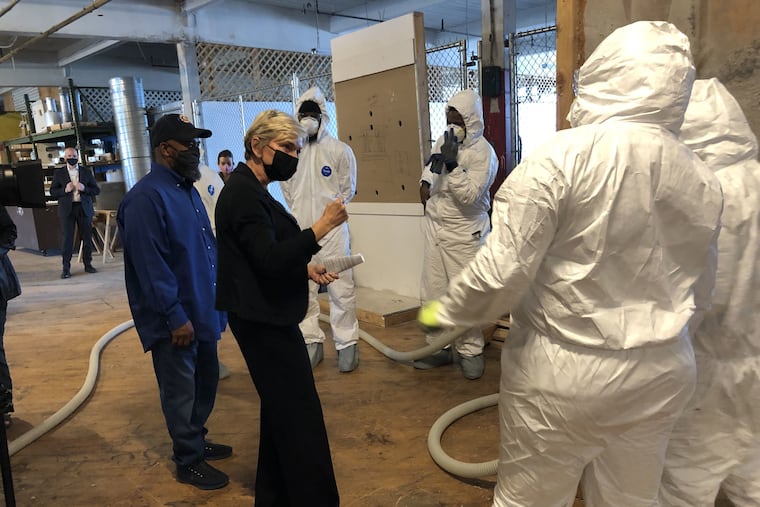 U.S. Secretary of Energy Jennifer M. Granholm (center) on a tour of the Energy Coordinating Agency, a nonprofit on W. Clearfield Street in Philadelphia's Kensington section. The facility trains disadvantaged youth and adults in green energy jobs. Head trainer Jackie Robinson, left, explains how the students are trained to insulate.