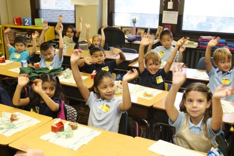 First-grade students raise their hands to show their "jagular" paws (school's mascot) at Andrew Jackson School in Philly in September 2013. A stepped-up effort by the city to collect the little-known School Income Tax, appears to be working. Just over 37M was collected from this tax, which benefits schools, in the last fiscal year. ( CHARLES FOX / Staff Photographer )