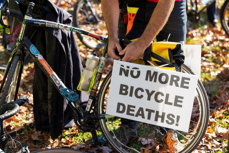 Daniel Paschall attaches a sign to his bike which reads "no more bicycle deaths!" at a memorial bike ride in Philadelphia in 2023.