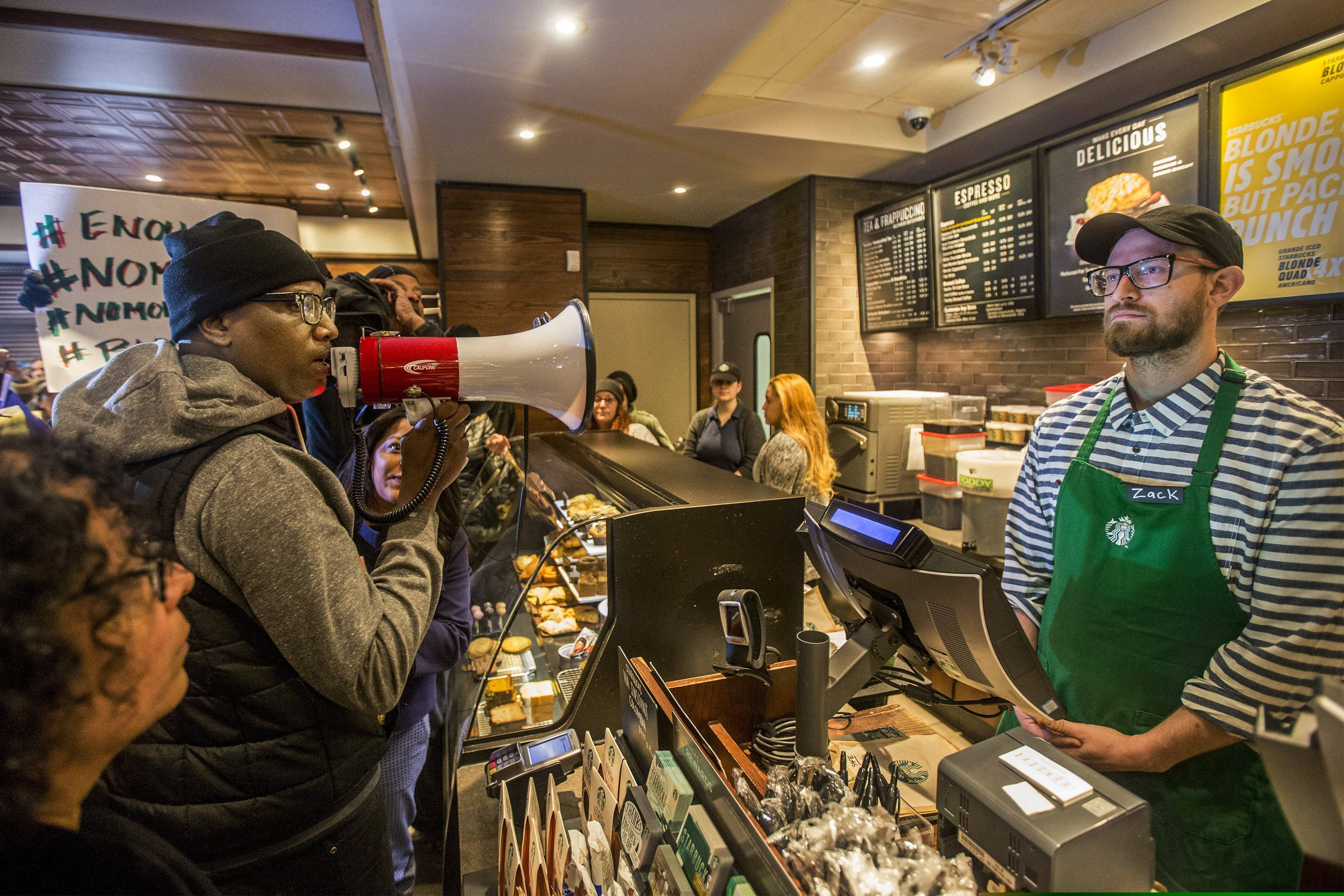 Activist Asa Khalif (left) uses a megaphone inside a Starbucks last April 15, demanding the firing of the manager who called police on two black men who had entered the store, but didn't make a purchase, resulting in their arrest.