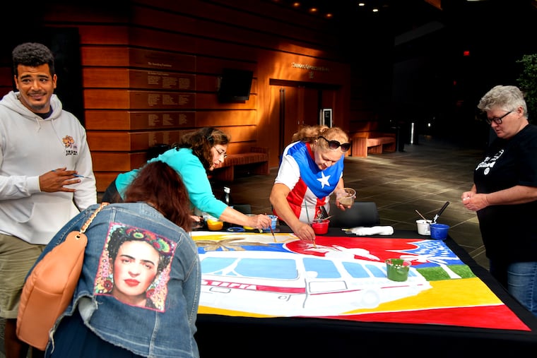 Mural Arts Philadelphia artist Sam Rodriguez (left) oversees the live creation of a painting by guests during a networking hour in the Kimmel Plaza Sept. 15, 2022 before the premiere of the short film La Guagua 47. The film, produced by Alba Martinez, introduces the significance of the SEPTA 47 bus to the thriving and inspiring culture of Philadelphia’s Latino community.