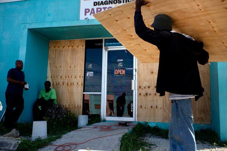 Men protect with wooden boards a shop window from the arrival of Hurricane Dorian in Freeport, Bahamas, Friday, Aug. 30, 2019. (AP Photo / Ramon Espinosa).