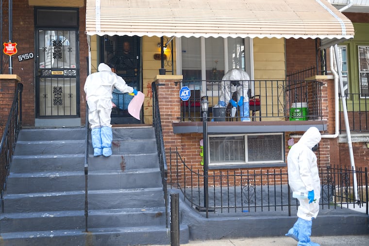 Biohazard and crime scene crews clean blood Tuesday outside the Webster Street home in West Philadelphia where authorities say a 75-year-old man who was armed with a gun was shot by police.