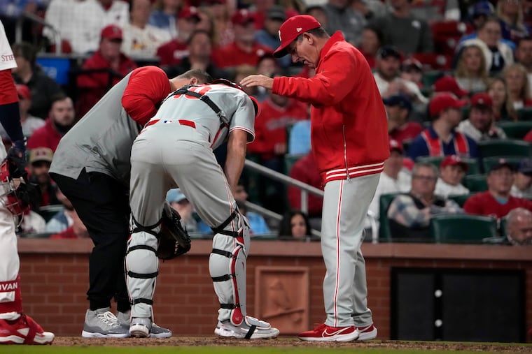 Philadelphia Phillies catcher J.T. Realmuto is checked on by Philadelphia Phillies manager Rob Thomson, right, after being injured during the seventh inning of a baseball game against the St. Louis Cardinals Tuesday, April 9, 2024, in St. Louis. Realmuto left the game. (AP Photo/Jeff Roberson)