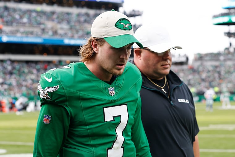 Former Eagles quarterback Kenny Pickett walks off the field with Dom DiSandro after suffering an injury during the team's win over the Dallas Cowboys in December.