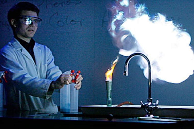 Mike Rheam, a demonstration coordinator in the chemistry department, shows how heavy-metal atoms produce colors in the heat of a flame. (MICHAEL S. WIRTZ / Staff Photographer)