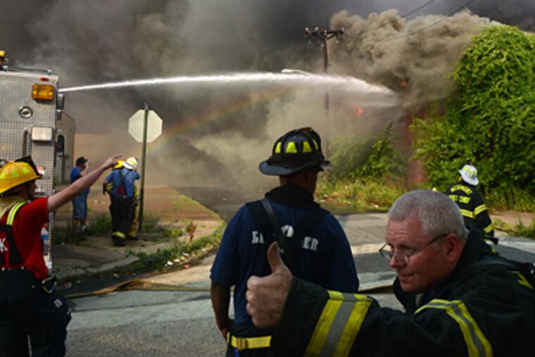 Firefighters move hoses into place while fighting the Camden fire. Blistering heat and wind Thursday caused it to spread quickly, a union official said. (Tom Gralish / Staff Photographer)